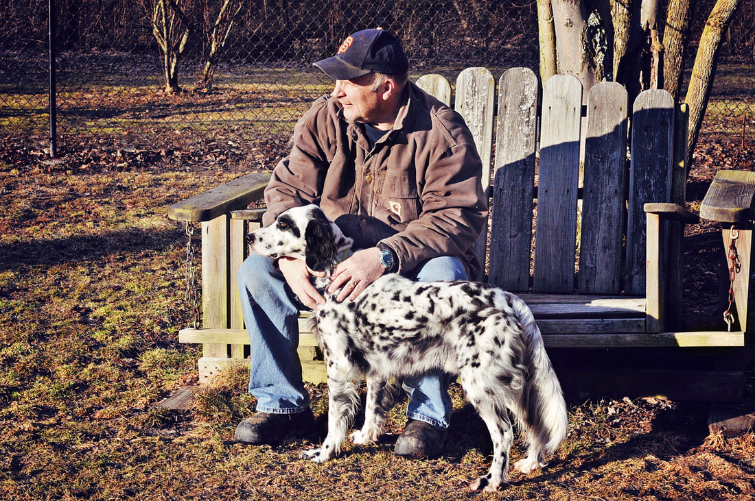 Man sitting on bench petting dog outdoors